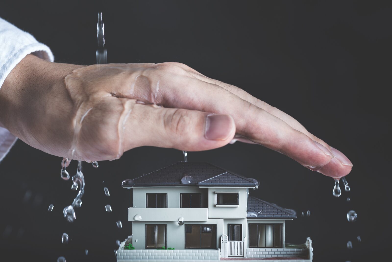 Hand schützt Haus vor Wasser
